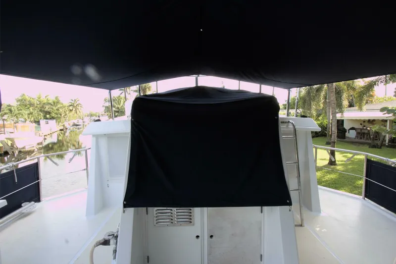 Ursa Minor Yacht Photos Pics 1988 Kadey-Krogen Krogen 54 yacht deck with canopy, docked near lush greenery.