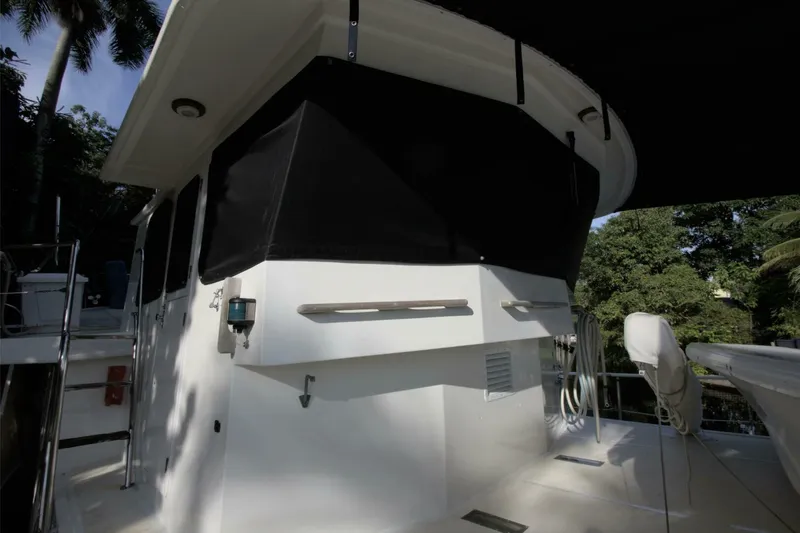 Ursa Minor Yacht Photos Pics 1988 Kadey-Krogen Krogen 54 yacht deck with black canopy and lush greenery background.