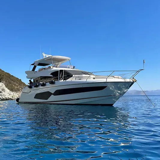  Yacht Photos Pics 2019 Sunseeker Manhattan 66 yacht on clear blue water near rocky coastline.