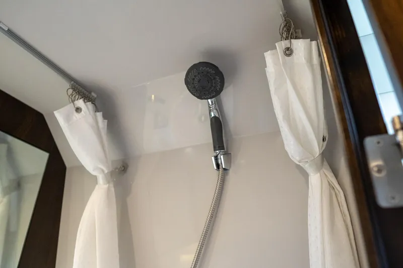 Di Blue Yacht Photos Pics Shower area in 2022 Cruisers Yachts 38 GLS with white curtains and handheld showerhead.