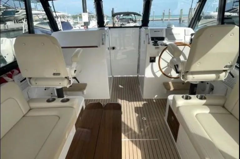 Lucky Boys Yacht Photos Pics 2022 MJM 3 boat interior with helm, seating, and wooden flooring at a marina.