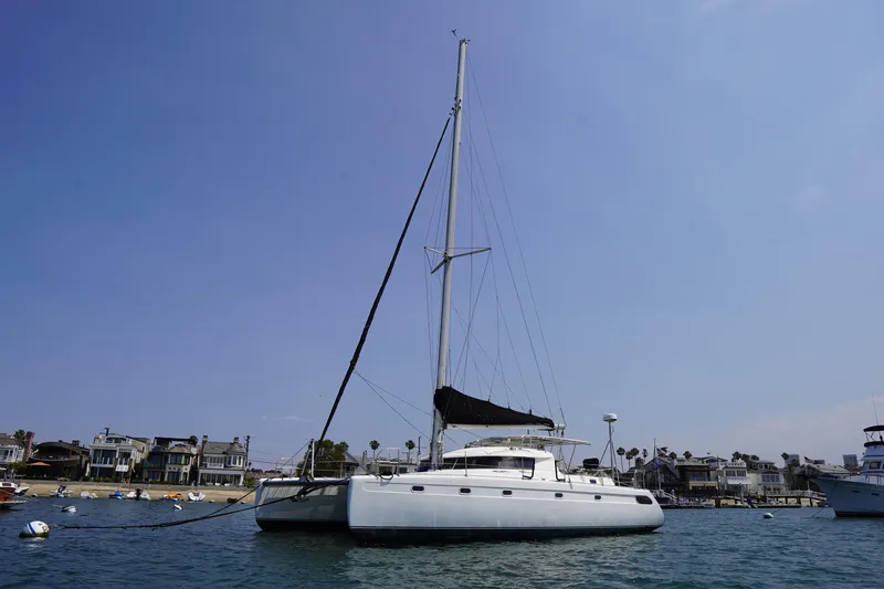 Loki Yacht Photos Pics Sailing catamaran Fountaine Pajot Venezia 42, 1995, anchored near coastal homes.