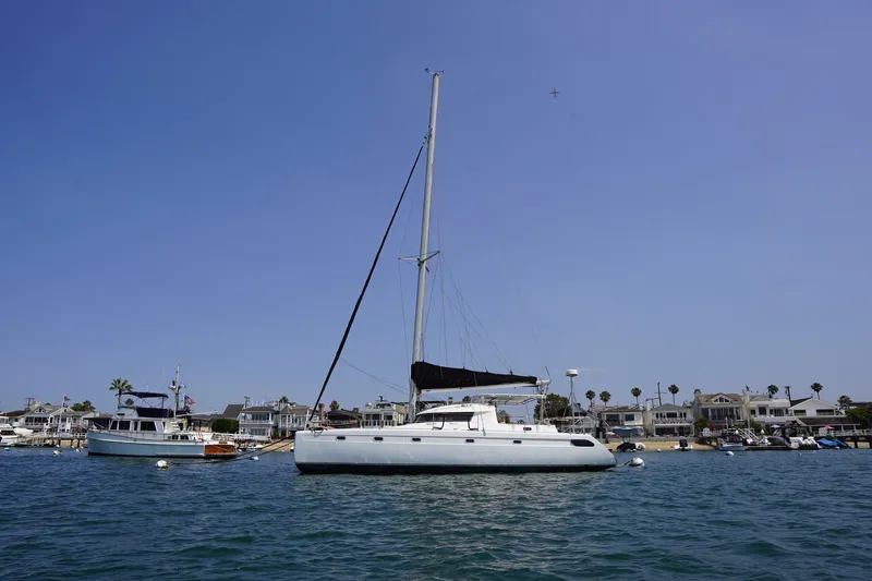 Loki Yacht Photos Pics Sailboat Fountaine Pajot Venezia 42, 1995 model, anchored near coastal homes.