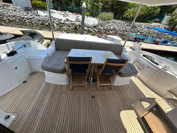 2021 Azimut 55 Fly @vallarta  Yacht Photos Pics Azimut 55 yacht deck with seating and table, 2021 model, docked by rocky shoreline.