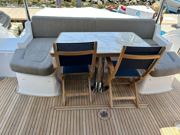 2021 Azimut 55 Fly @vallarta  Yacht Photos Pics Outdoor seating area on 2021 Azimut 55 yacht with wooden chairs and marble table.