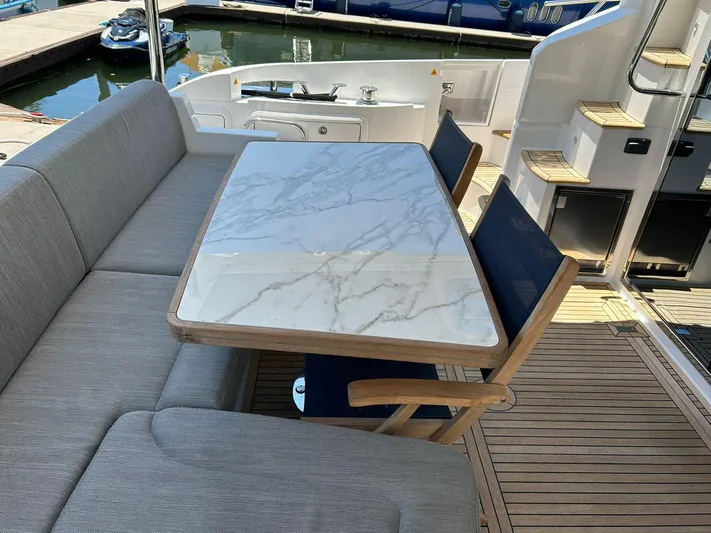 2021 Azimut 55 Fly @vallarta  Yacht Photos Pics Outdoor seating area on 2021 Azimut 55 yacht with marble table and cushioned chairs.