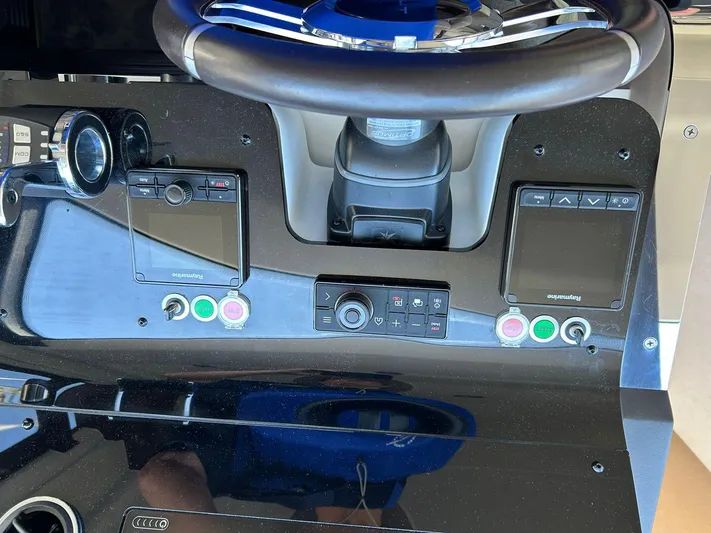2021 Azimut 55 Fly @vallarta  Yacht Photos Pics Control panel of a 2021 Azimut 55 yacht with steering wheel and navigation screens.