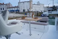 Rhea 27 Open V2 boat, 2026 model, docked with dining setup, historic buildings in background.
