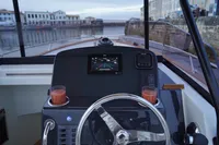 Steering console of 2026 Rhea 27 Open V2 boat with navigation screen and drinks.
