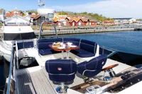 Luxurious 2010 Storebro 435 Commander yacht with elegant seating, docked near charming coastal village.