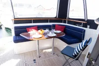 Storebro 435 Commander 2010 yacht dining area with table, blue seating, and nautical decor.