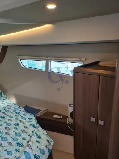 P Yacht Photos Pics 2018 Sealine C330 cabin interior with bed, window, and wooden storage cabinet.