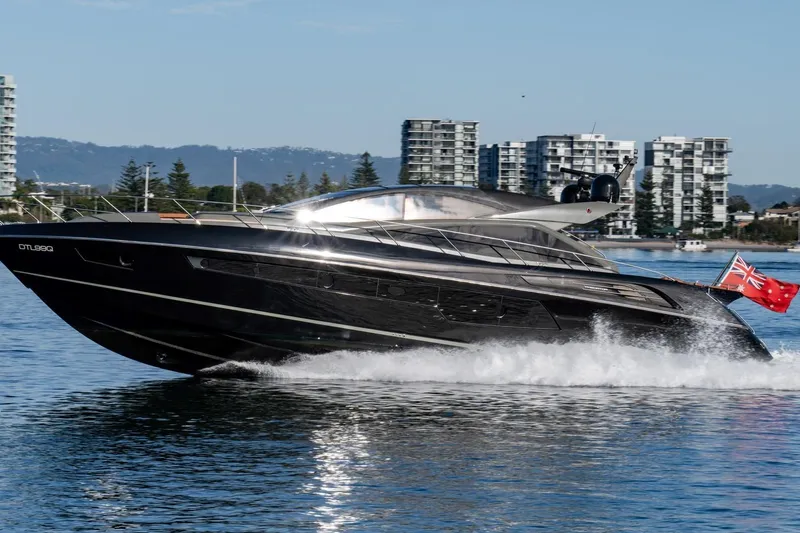 Zaza Yacht Photos Pics 2013 Sunseeker Predator 68 yacht cruising on water, cityscape in background.