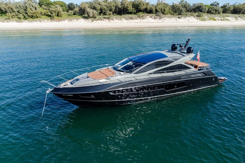 Zaza Yacht Photos Pics Luxurious 2013 Sunseeker Predator 68 yacht cruising near a scenic shoreline.