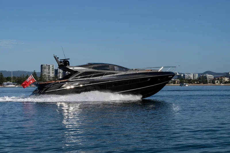 Zaza Yacht Photos Pics 2013 Sunseeker Predator 68 yacht cruising on calm waters near a cityscape.