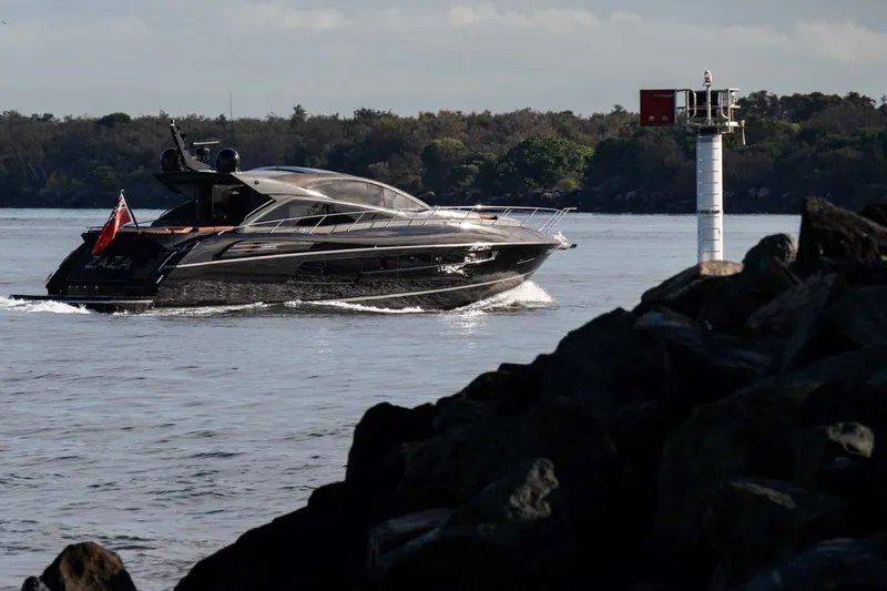 Zaza Yacht Photos Pics Luxurious 2013 Sunseeker Predator 68 yacht cruising near rocky shoreline and lighthouse.
