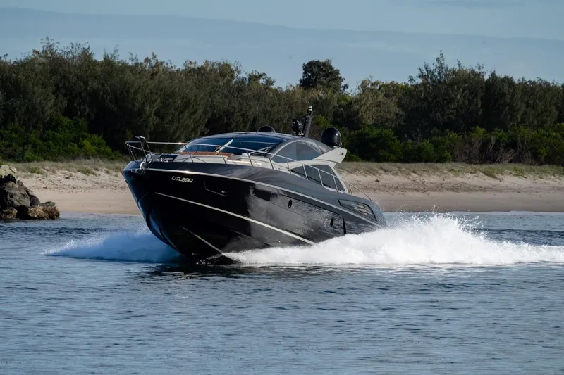 Zaza Yacht Photos Pics 2013 Sunseeker Predator 68 yacht cruising on water near a sandy shoreline.