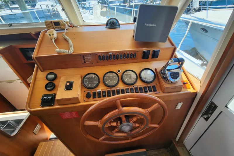  Yacht Photos Pics Helm of 2003 Mainship 43 Trawler Aft Cabin with wooden wheel and navigation instruments.