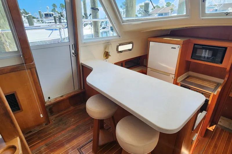  Yacht Photos Pics 2003 Mainship 43 Trawler Aft Cabin interior with kitchenette, stools, and wooden flooring.
