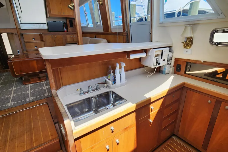  Yacht Photos Pics 2003 Mainship 43 Trawler Aft Cabin kitchen with wooden cabinetry and dual sink.