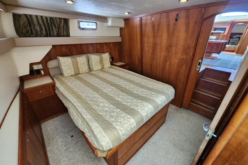  Yacht Photos Pics Luxurious cabin interior of 2003 Mainship 43 Trawler Aft Cabin with cozy bed and wooden finish.