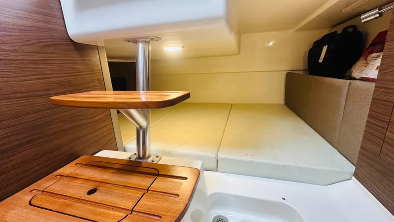  Yacht Photos Pics 2021 Boston Whaler 325 Conquest cabin interior with wooden table and cushioned seating.