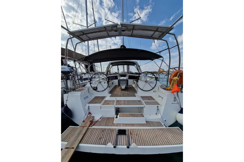  Yacht Photos Pics 2014 Beneteau Oceanis 48 sailboat with dual steering wheels, docked under a blue sky.
