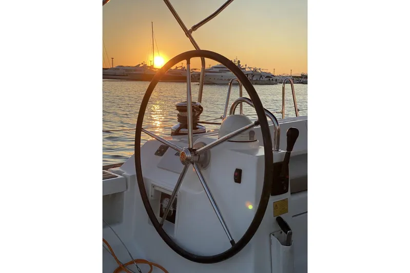  Yacht Photos Pics Steering wheel of 2014 Beneteau Oceanis 48 yacht at sunset, docked in marina.