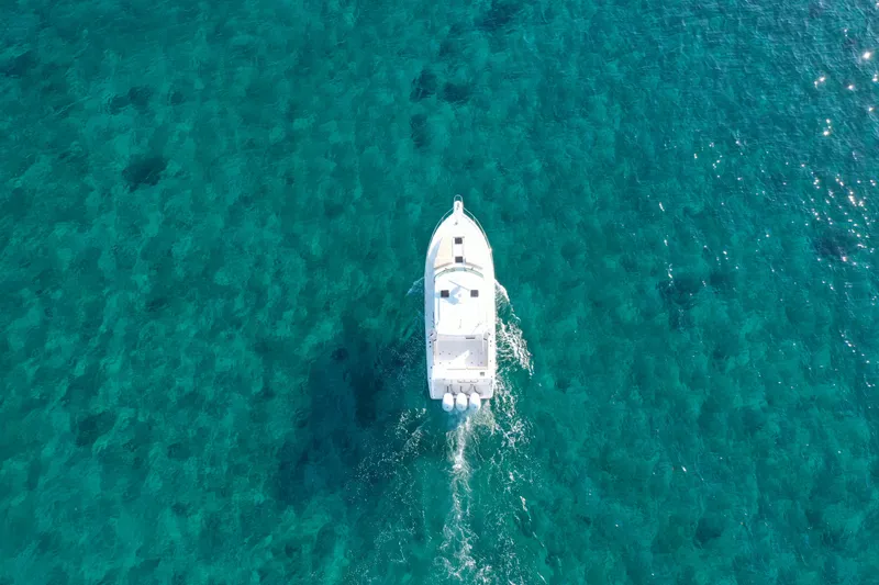 Mama Lucia Yacht Photos Pics Aerial view of a 2017 Pursuit 385 Offshore boat cruising on clear blue water.