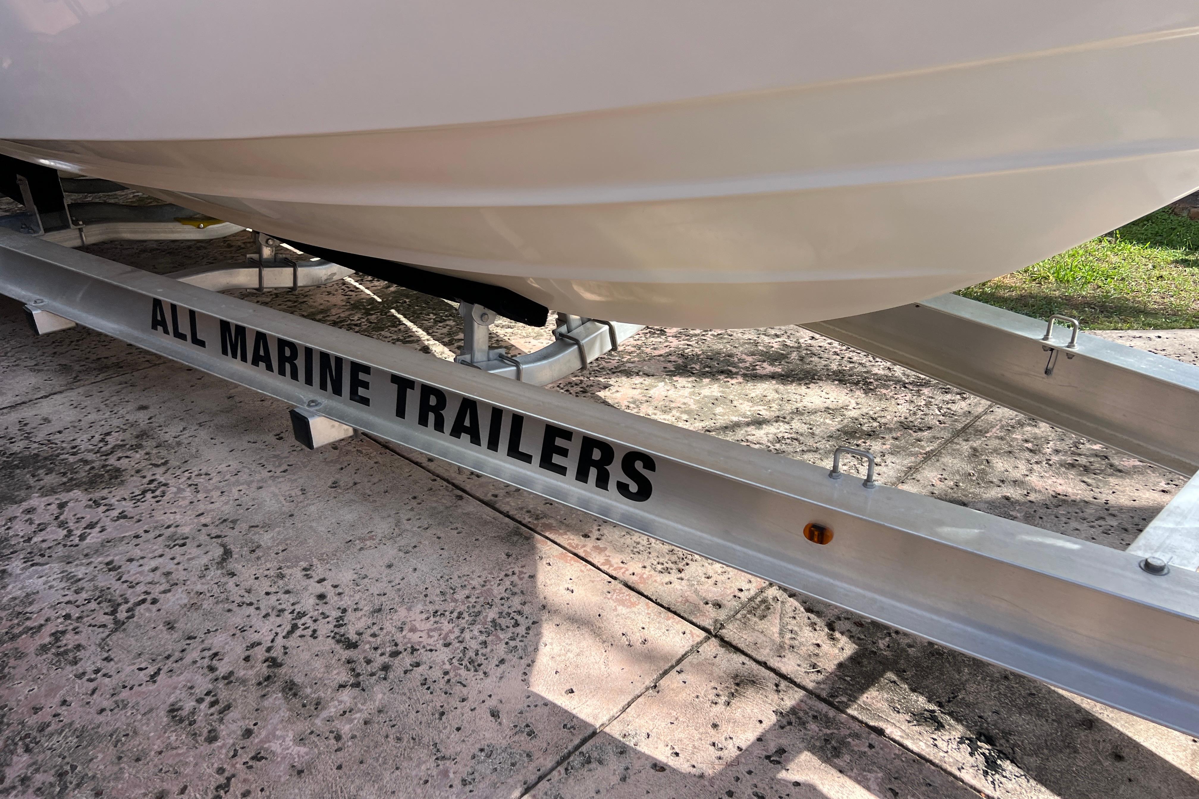 1999 Pursuit 2470 Walkaround boat on All Marine Trailers, parked on concrete.