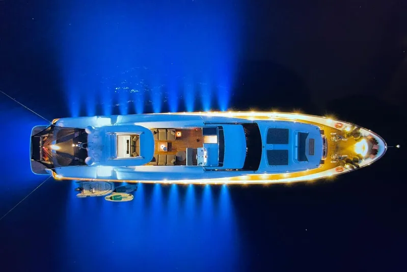 Axella Yacht Photos Pics Aerial view of illuminated 1991 Crestitalia 33m yacht at night, glowing blue in water.