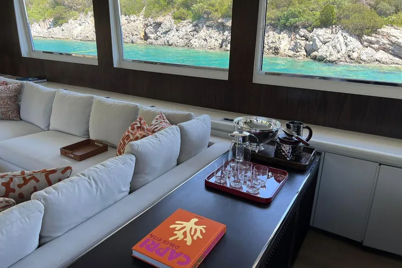 Axella Yacht Photos Pics Luxurious yacht interior with white sofa, decorative pillows, and ocean view through large windows.