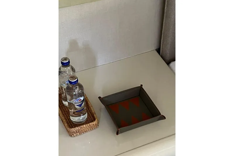 Axella Yacht Photos Pics Two water bottles on a wicker tray beside a decorative tray on a table.