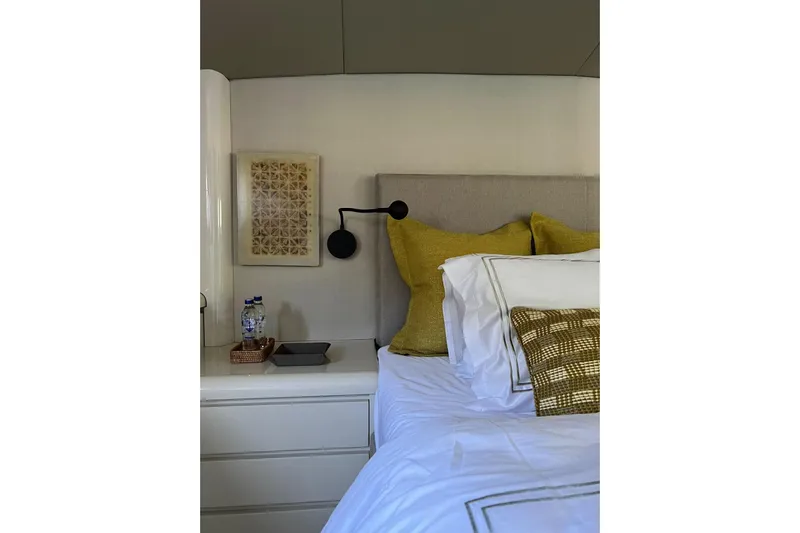 Axella Yacht Photos Pics Luxurious yacht bedroom with modern decor, featuring yellow pillows and elegant wall art.