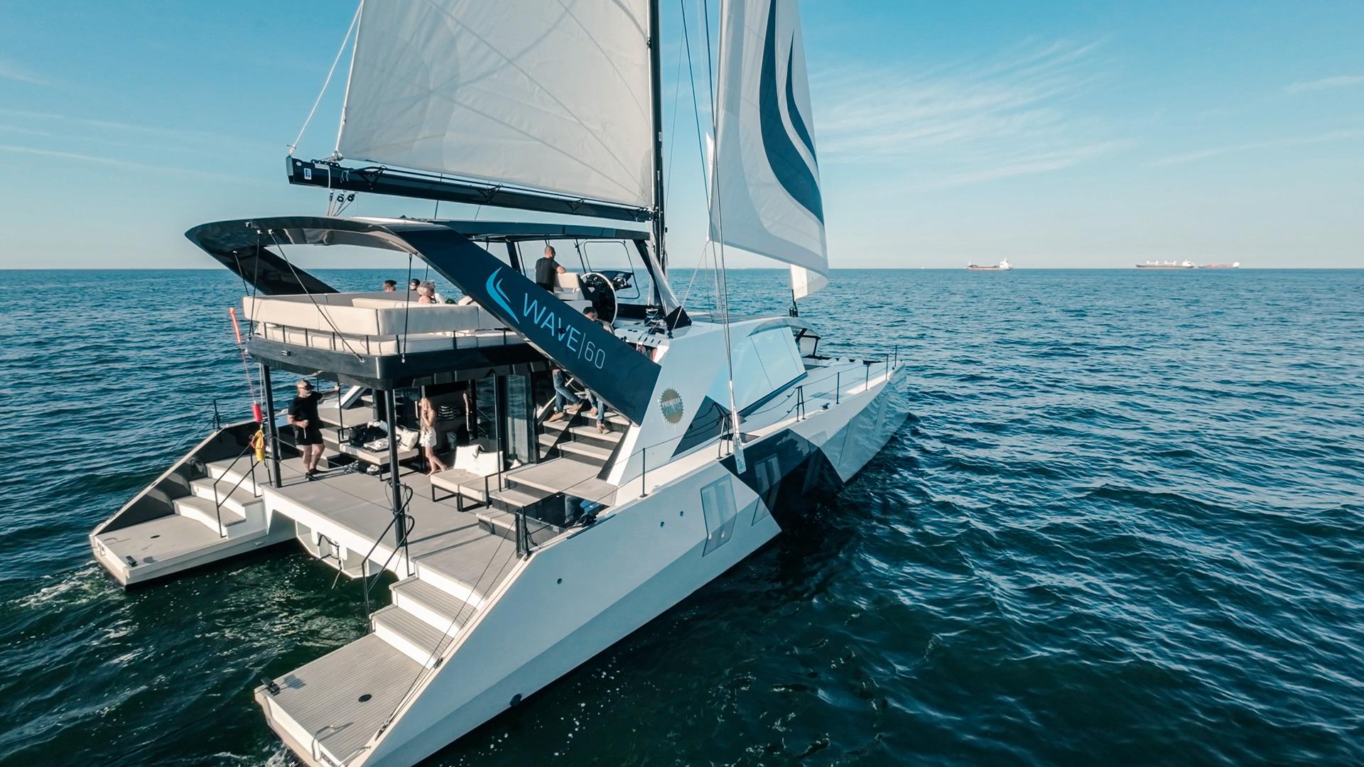 Sailing catamaran Wave 60, 2024 model, cruising on open sea under clear skies.