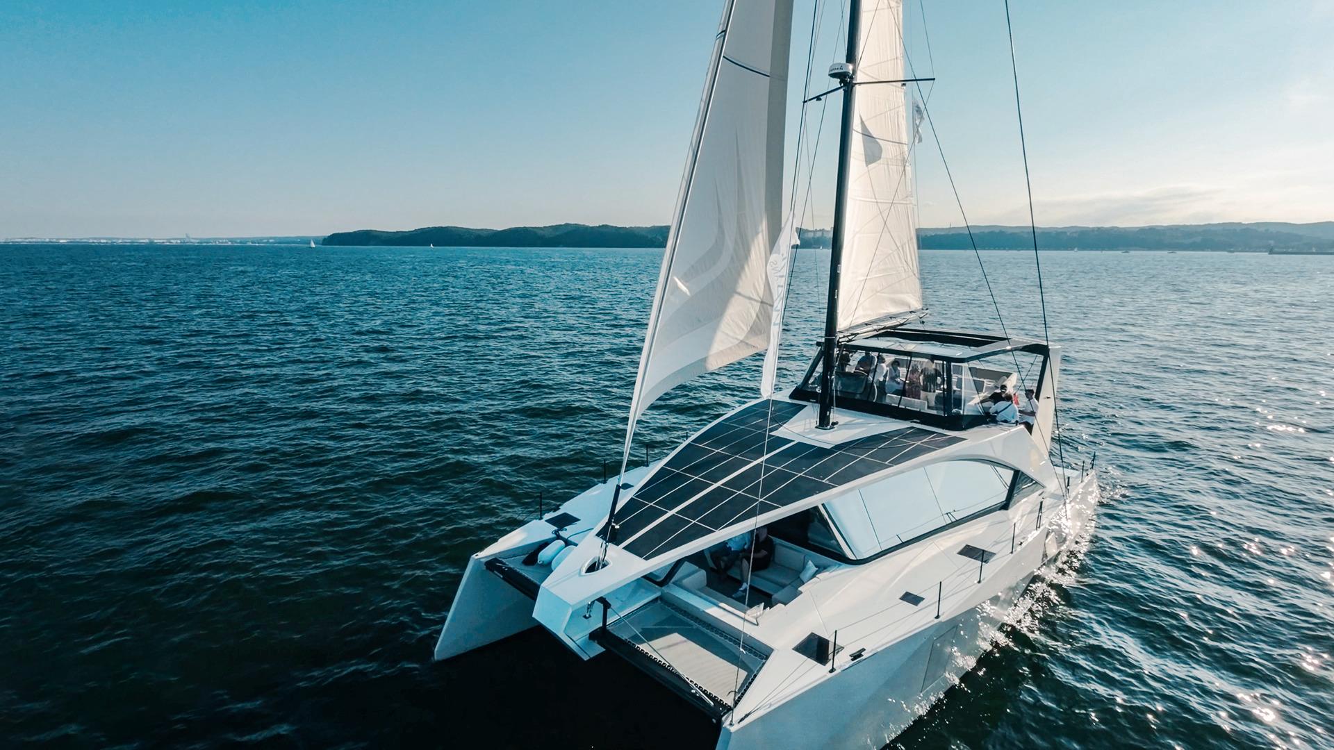 2024 Wave 60 catamaran sailing on open sea under clear blue sky.