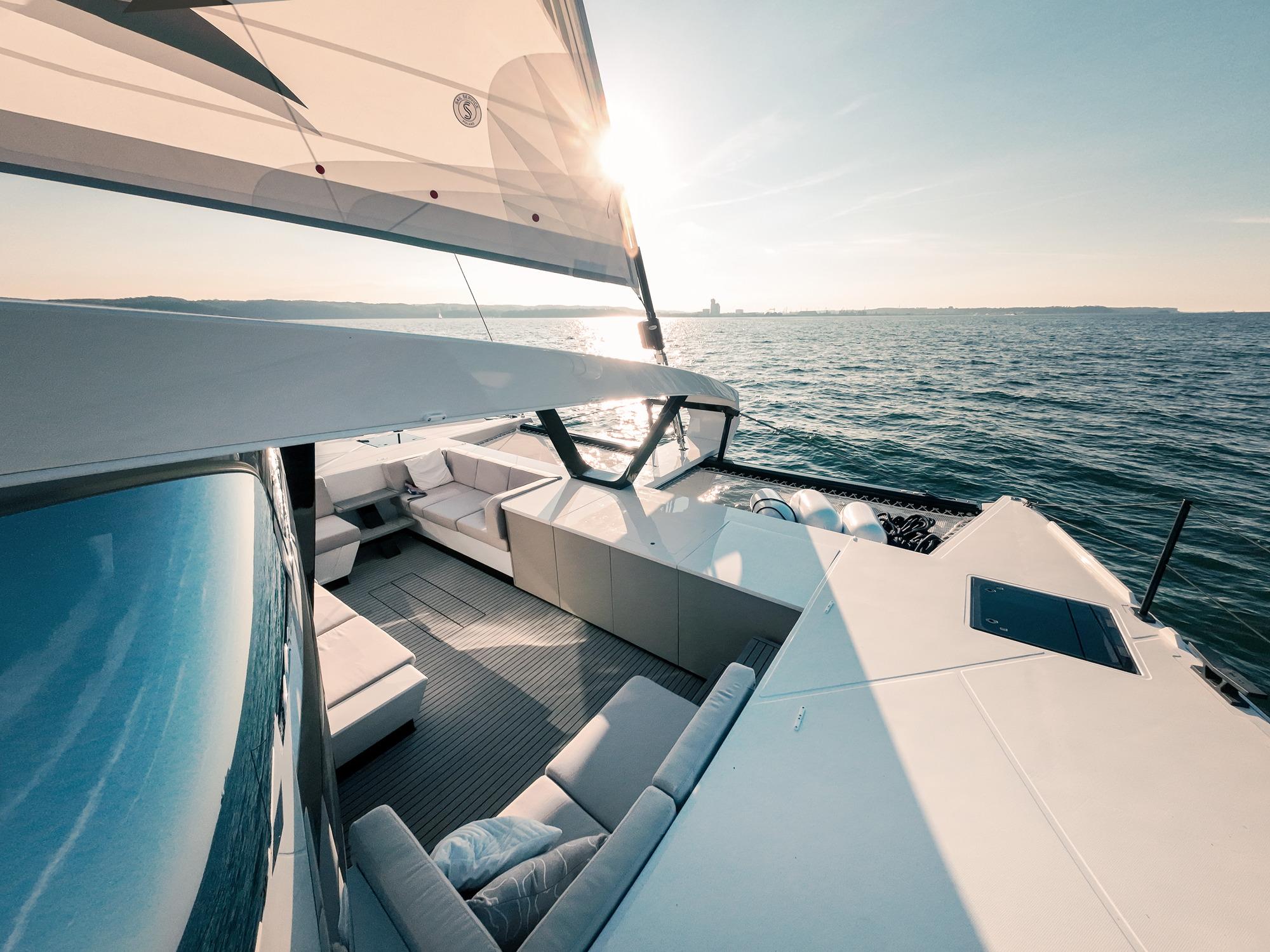 Luxurious 2024 Wave 60 yacht with spacious deck, sailing on open sea at sunset.