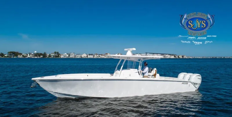  Yacht Photos Pics 2024 Jupiter 34 boat cruising on a sunny day with coastal town in the background.