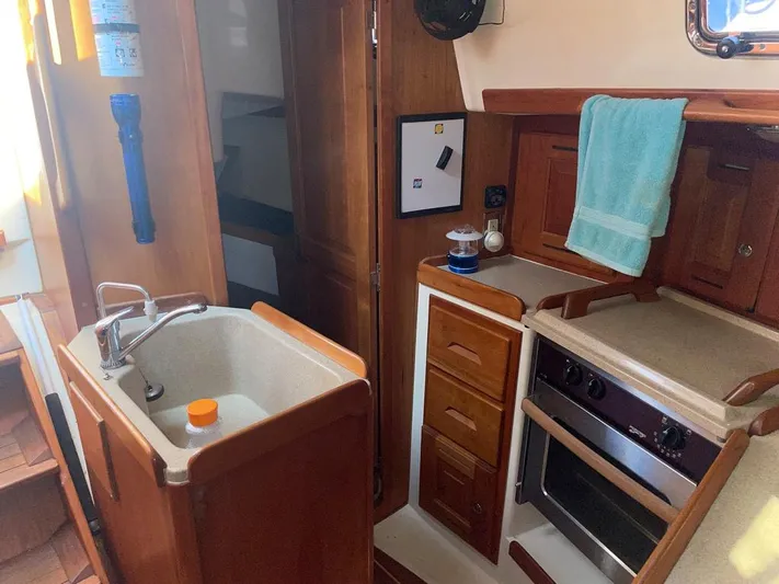 Bell Canto Yacht Photos Pics Interior of 2006 Tartan 3400 sailboat kitchen with sink, stove, and wooden cabinetry.