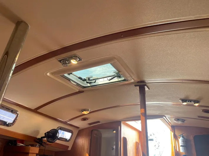 Bell Canto Yacht Photos Pics Interior view of a 2006 Tartan 3400 sailboat, featuring a skylight and wooden accents.