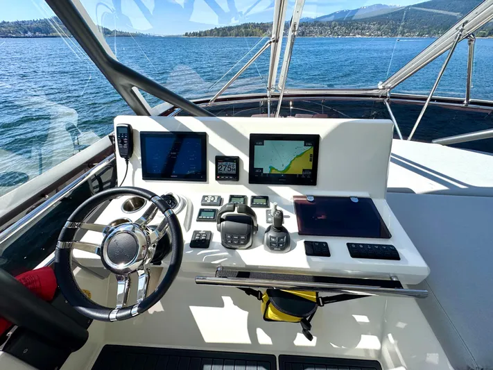 M.y. Blu Dayz Yacht Photos Pics Helm of 2023 Prestige 520 yacht with navigation screens and steering wheel, overlooking scenic waters.