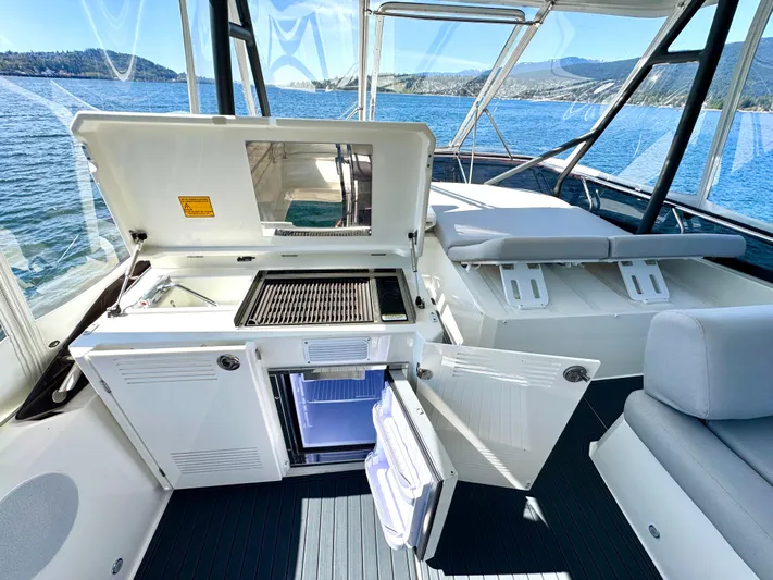 M.y. Blu Dayz Yacht Photos Pics 2023 Prestige 520 yacht interior with open kitchenette, grill, and seating, overlooking scenic water views.