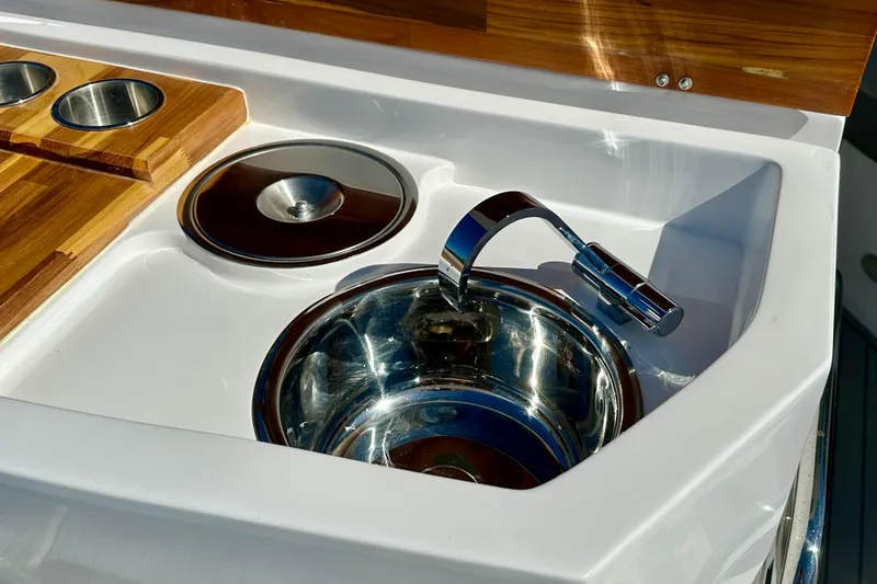  Yacht Photos Pics 2024 NX 360 Sport Coupe kitchen sink with wooden cutting board and stainless steel faucet.