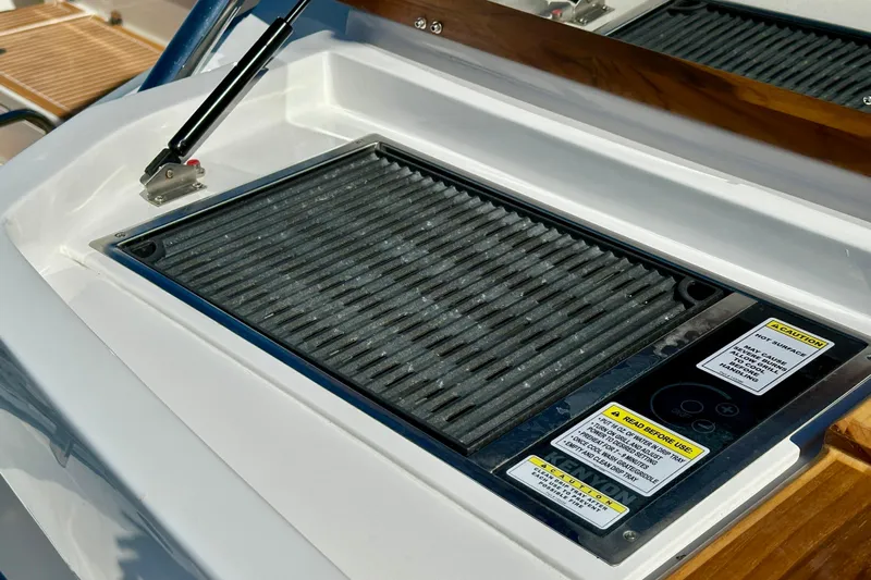  Yacht Photos Pics Built-in grill on 2024 NX 360 Sport Coupe boat deck, featuring safety instructions.