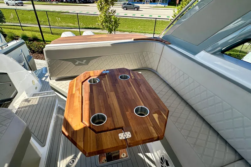  Yacht Photos Pics 2024 NX 360 Sport Coupe interior with wooden table and quilted seating.
