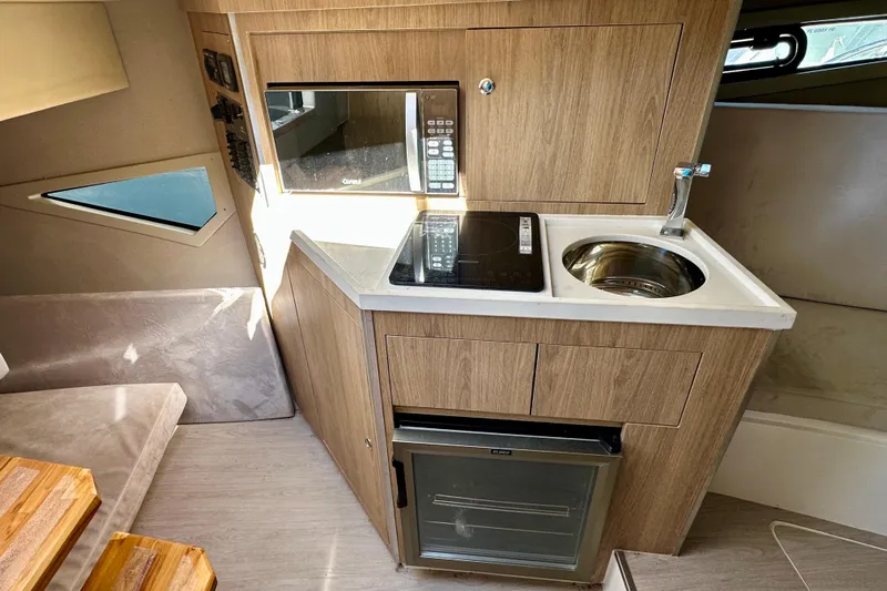  Yacht Photos Pics Compact kitchen in 2024 NX 360 Sport Coupe with microwave, sink, and stove.