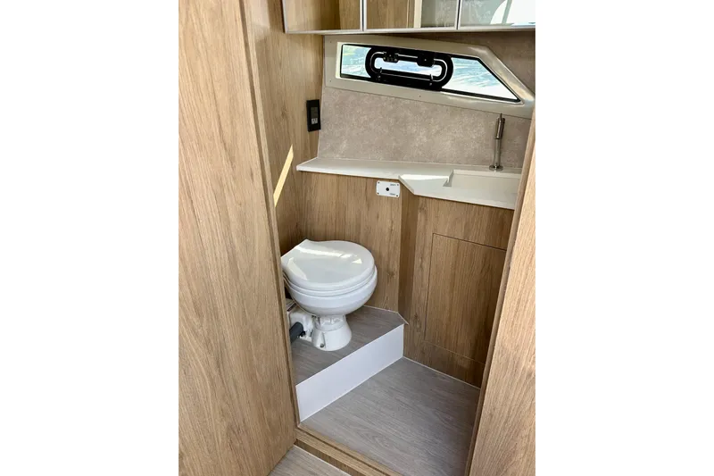  Yacht Photos Pics 2024 NX 360 Sport Coupe bathroom with wood finish, compact toilet, and sink.