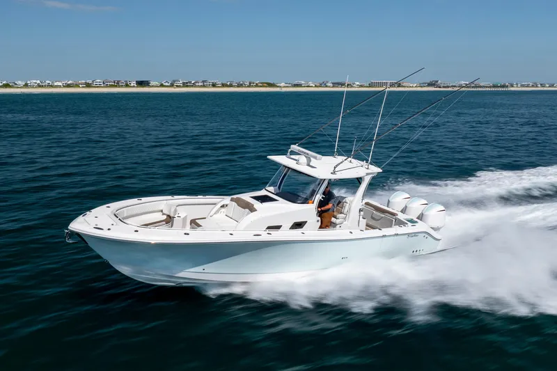  Yacht Photos Pics 2021 Edgewater 370CC boat cruising on open water with coastal background.