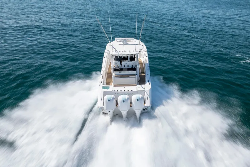  Yacht Photos Pics 2021 Edgewater 370CC boat speeding on open water, rear view.