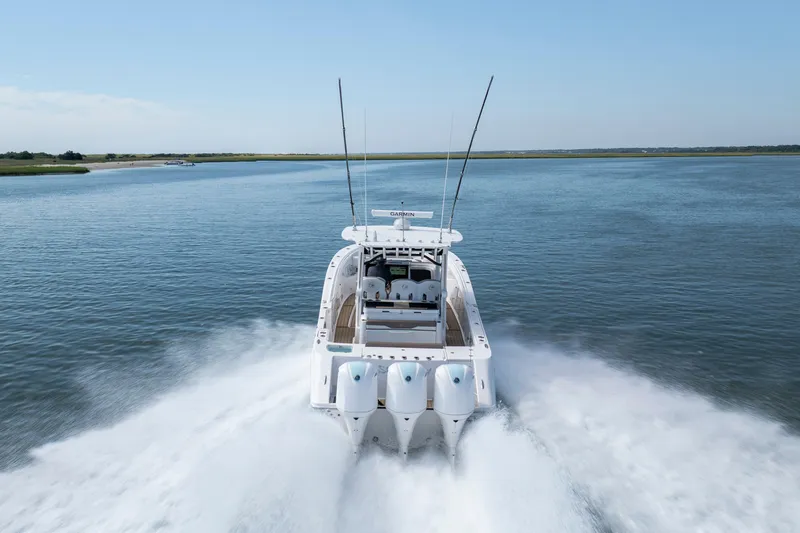  Yacht Photos Pics 2021 Edgewater 370CC boat speeding on open water, rear view.